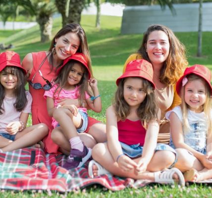 Friends enjoying a sunny day picnic on grass with bucket hats and smiles in a Portuguese park.